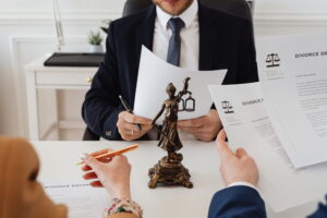 lawyer holding paperwork across table from woman signing and man holding more divorce paperwork