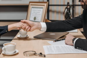 lawyer shaking hands with woman over desk with divorce paperwork on it